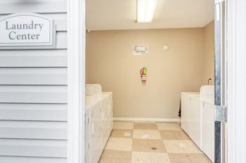 a laundry room with white cabinets and a sign that reads laundry center at The Oliver Apartment Homes, Mississippi